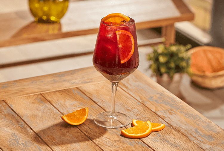 Taça de tinto de verano com gelo e rodelas de laranja